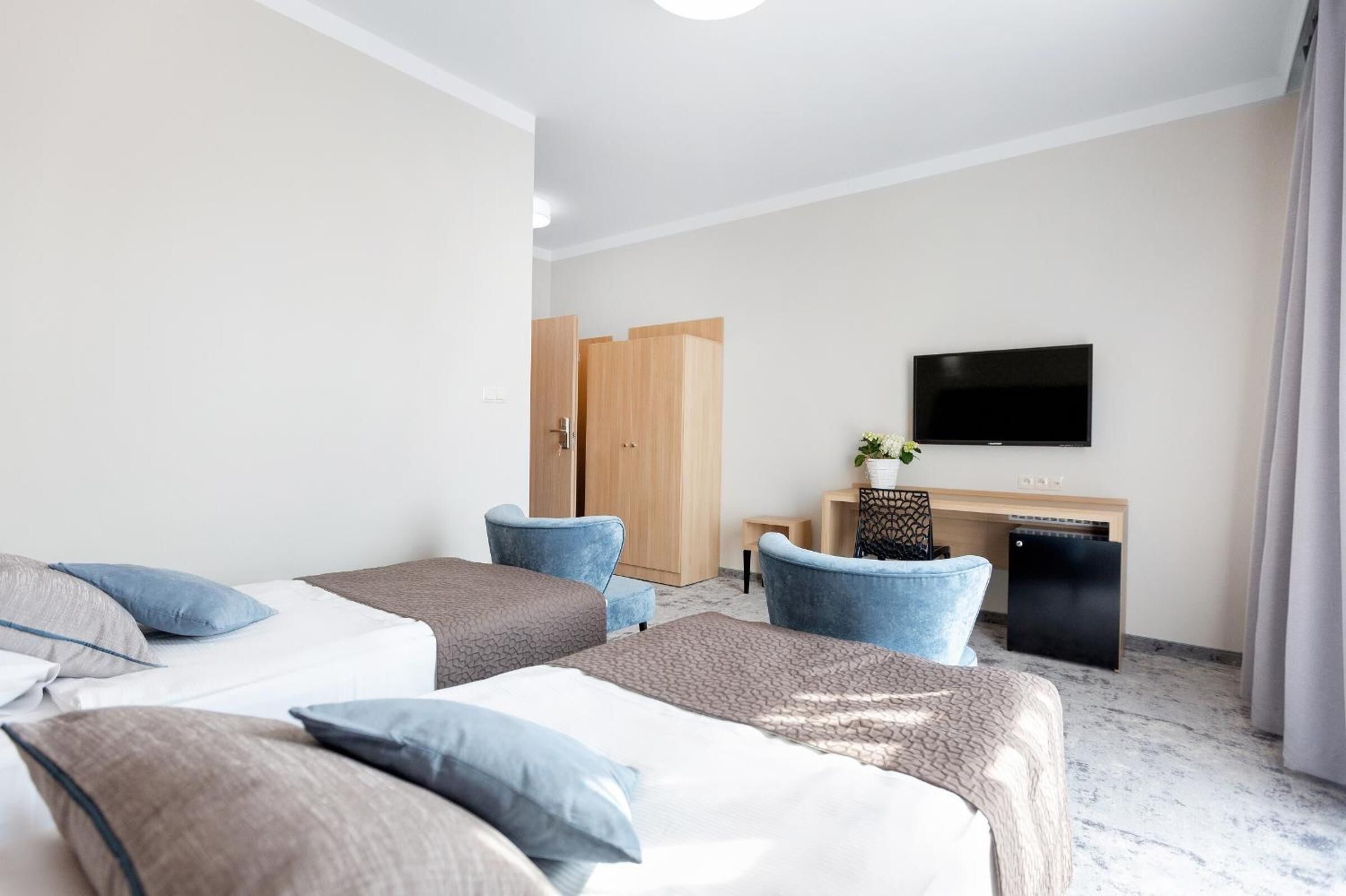 Una habitación de hotel con dos camas, un escritorio, televisor y armario.