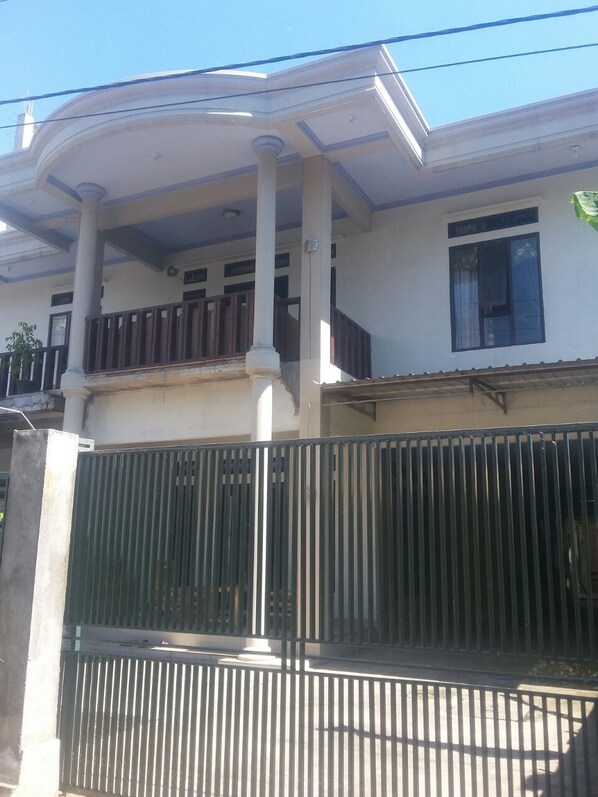 A two-story building with a balcony, a gated entrance, and a clear sky. - Restu By View Hotel (Bayan)