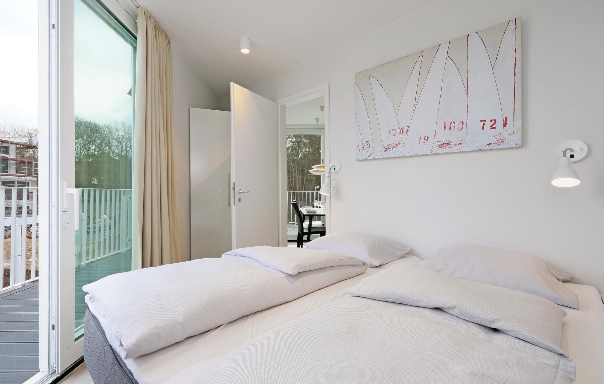 Een hotelkamer met twee bedden, een balkon, uitzicht en een schilderij aan de muur.