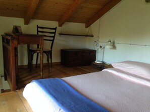 A bedroom with a wooden ceiling, a desk with a chair, a bedside table, and a lamp. - Ca' de l'Ase B&B (Giusvalla)