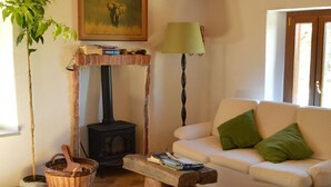 Una sala de estar acogedora con un sofá, una mesa de centro de madera, una chimenea, una lámpara y un cuadro de un elefante.