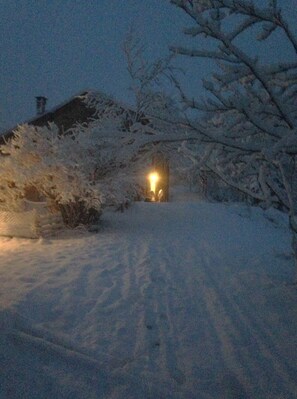 A snow-covered landscape with a house and a lit window. - Ca' de l'Ase B&B (Giusvalla)