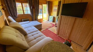 A wooden interior with a sofa, a television, and a window with curtains. - Prigge vacation apartment (Brodersby)