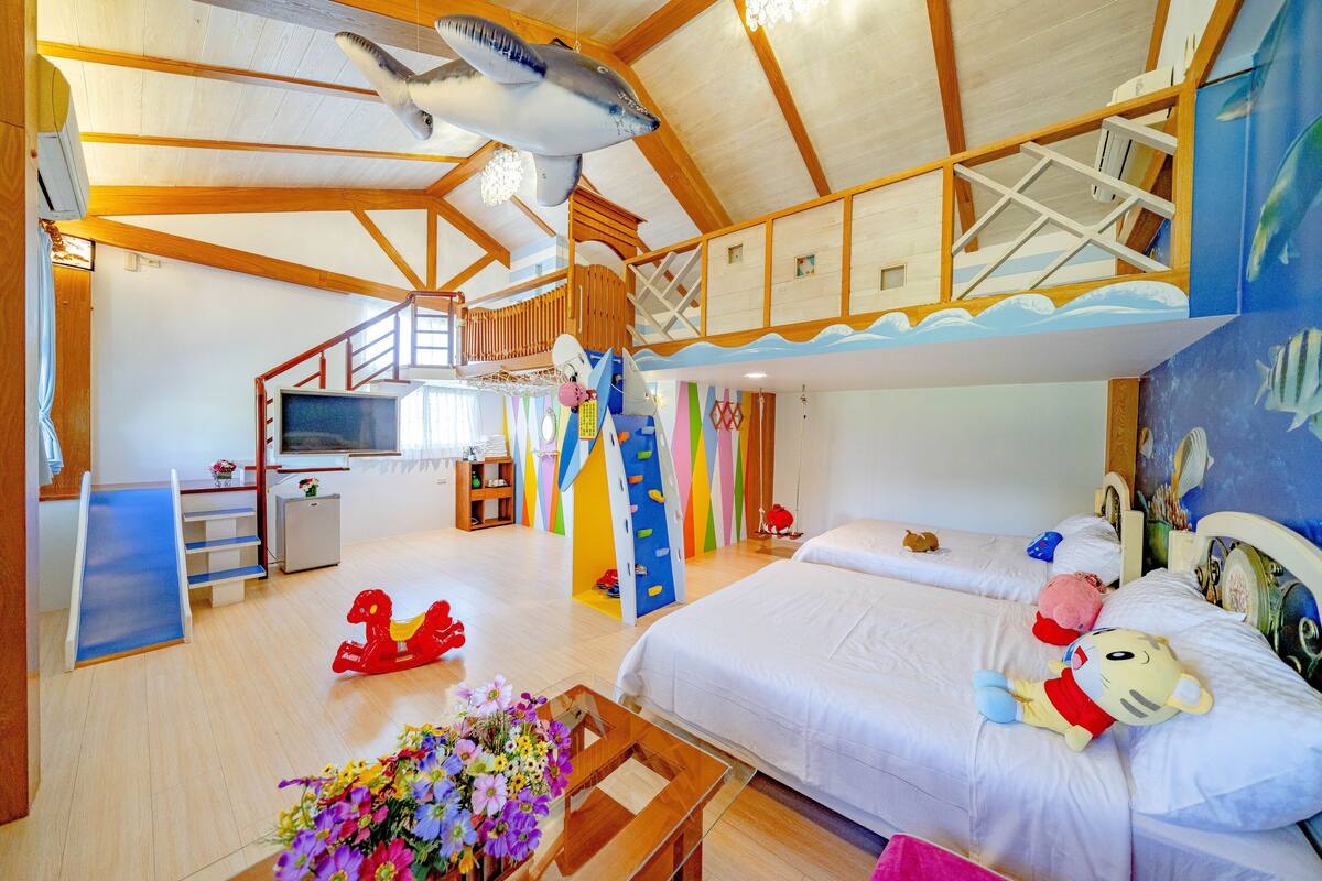 Una habitación amplia con una cama grande, un escritorio y una escalera que lleva a un nivel superior.