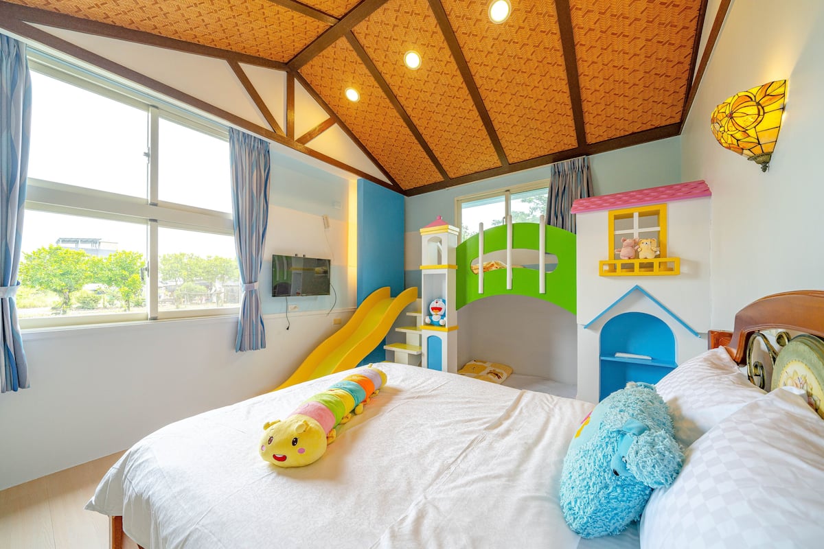 Un dormitorio infantil con cama, zona de juegos y ventana con cortinas.
