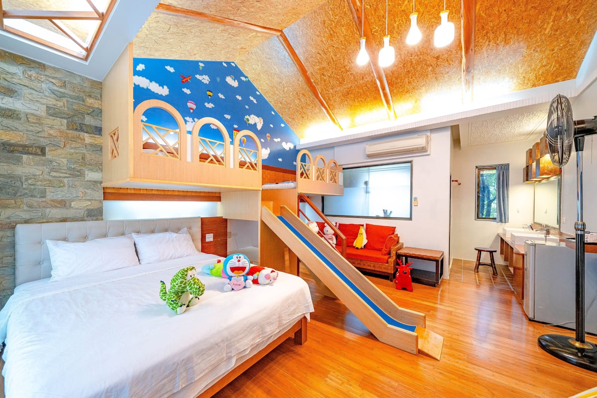 Un dormitorio con una cama litera, un tobogán y una zona de escritorio.