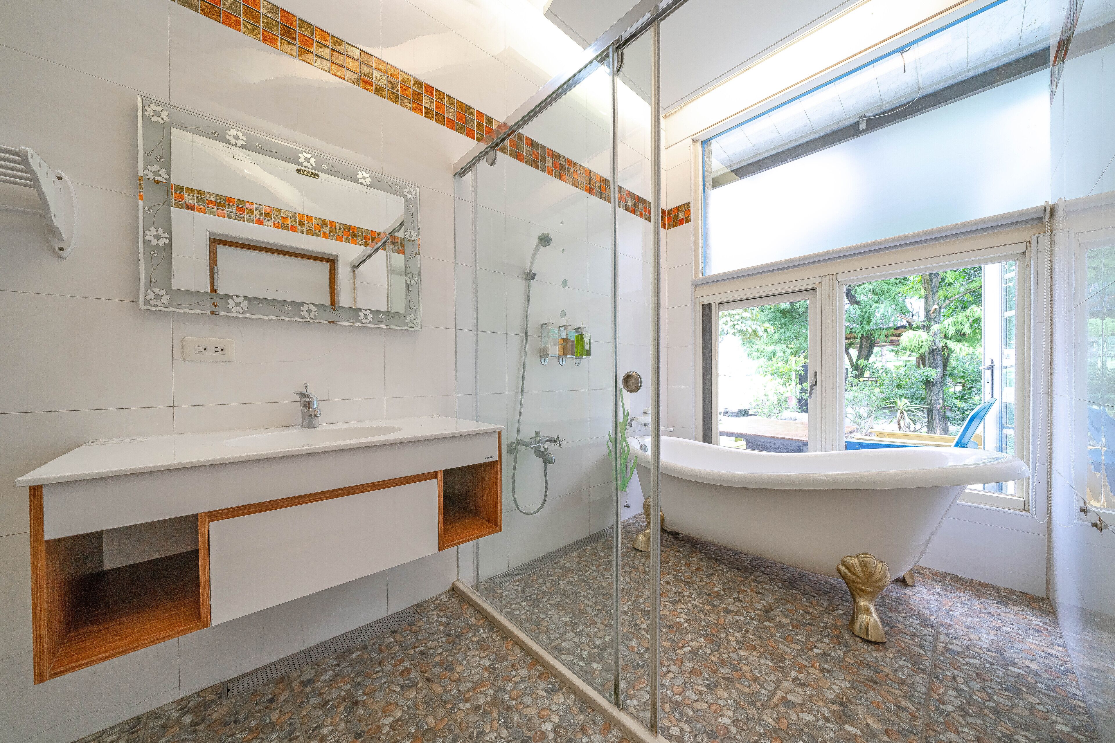 A bathroom with a glass-enclosed shower, a freestanding bathtub, and a vanity with a mirror.