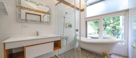 A bathroom with a glass-enclosed shower, a freestanding bathtub, and a vanity with a mirror.