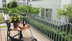 A balcony with a table, chairs, a vase of flowers, and a bottle of wine. - Holiday apartment 01 Villa Seeblick on the beach of Binz - Villa Seeblick Binz (Binz)