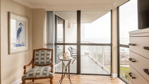 A room with a wooden chair, a small table, and a large window with a balcony view. - Beautiful Views, 4 Bedroom Gulf Front with 2 Master Suites, Sleeps 12 (Miramar Beach)
