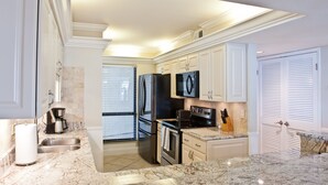 A kitchen with white cabinets, a stainless steel refrigerator, a microwave, and a stove. - Beautiful Views, 4 Bedroom Gulf Front with 2 Master Suites, Sleeps 12 (Miramar Beach)