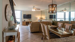 A spacious living area with a dining table, sofas, and a large mirror. - Beautiful Views, 4 Bedroom Gulf Front with 2 Master Suites, Sleeps 12 (Miramar Beach)