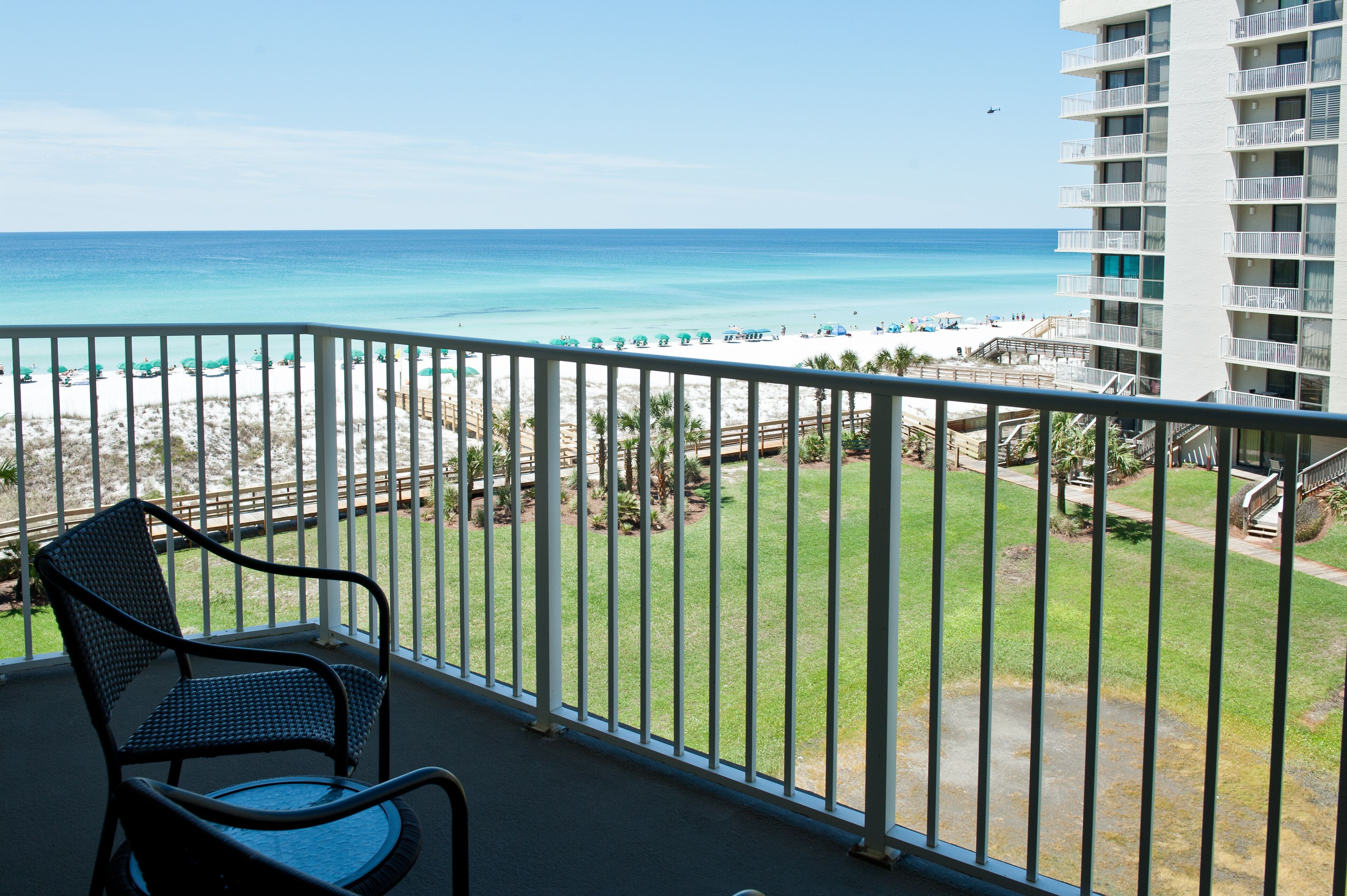 A balcony with a view of the beach and ocean.