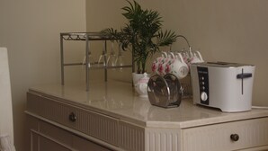 A kitchen counter with a toaster, a glass holder, a potted plant, and a teapot. - Brooks (Nairobi)