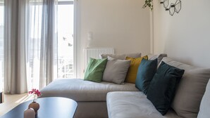 Ein modernes Wohnzimmer mit einem beigefarbenen Sofa, einem schwarzen Couchtisch und einer Vase mit Blumen.