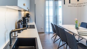 Eine moderne Küche mit Einbauherd, einer Kaffeemaschine und einem Essbereich mit Tisch und Stühlen.
