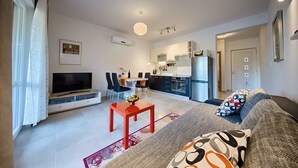 Een modern appartement met een woonkamer, eethoek, keuken en een balkon.
