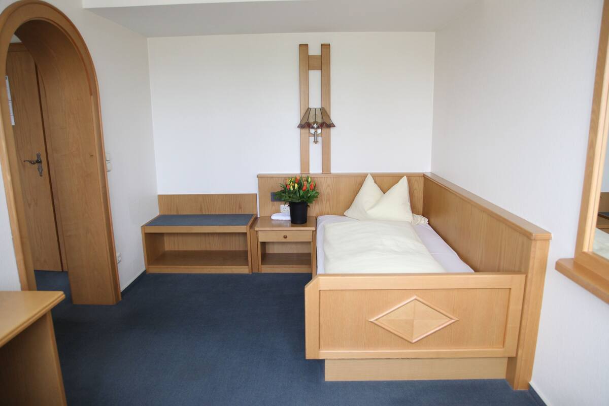 Un dormitorio con cama de madera, mesita de noche, escritorio y lámpara.