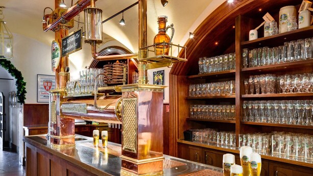 A bar area with a copper beer tap, shelves of beer glasses, and a wooden counter. - Brauereigasthof Buergerbraeu (Bad Reichenhall)