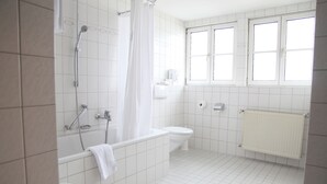 A bathroom with a bathtub, toilet, and window. - Brauereigasthof Buergerbraeu (Bad Reichenhall)