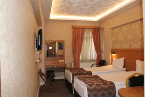 Una habitació d'hotel amb dos llits individuals, un escriptori amb cadira, un mirall i una finestra amb cortines.