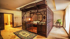 Un lit traditionnel à baldaquin, orné de sculptures complexes et surmonté d’un tapis à motifs.