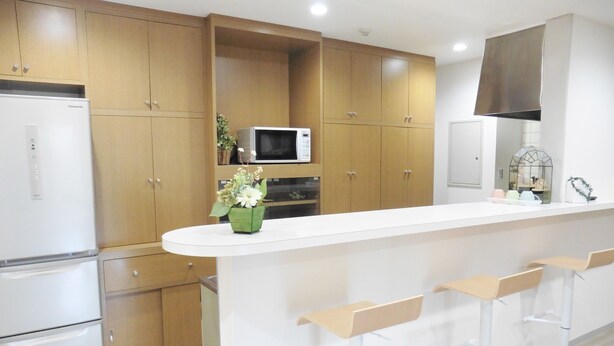 Une cuisine moderne avec des meubles en bois, un plan de travail blanc, un four à micro-ondes et un réfrigérateur.