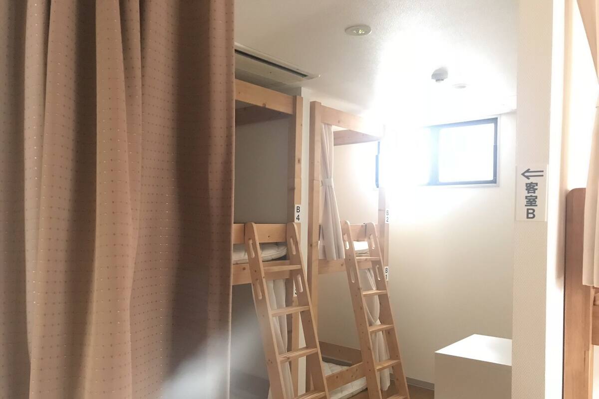 Une pièce avec un lit superposé, une échelle, une petite fenêtre et une pancarte indiquant la chambre B.