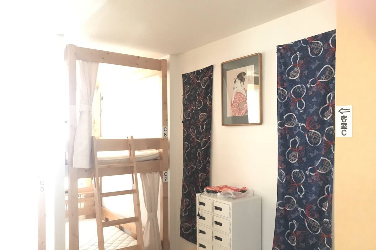 Une chambre avec des lits superposés, une commode et un rideau.