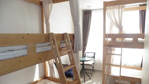 Une chambre avec deux lits superposés, une petite table et une chaise.