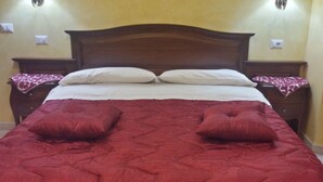Una cama con cabecera de madera, dos mesitas de noche y una colcha roja.