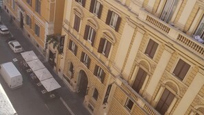 Un edificio de varios pisos con fachada amarilla y una furgoneta blanca estacionada en la calle.