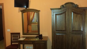 Una habitación con un escritorio de madera, una silla, un espejo y un armario.