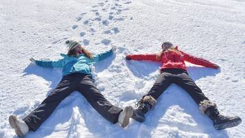 Two people lying on snow with their arms and legs spread out.