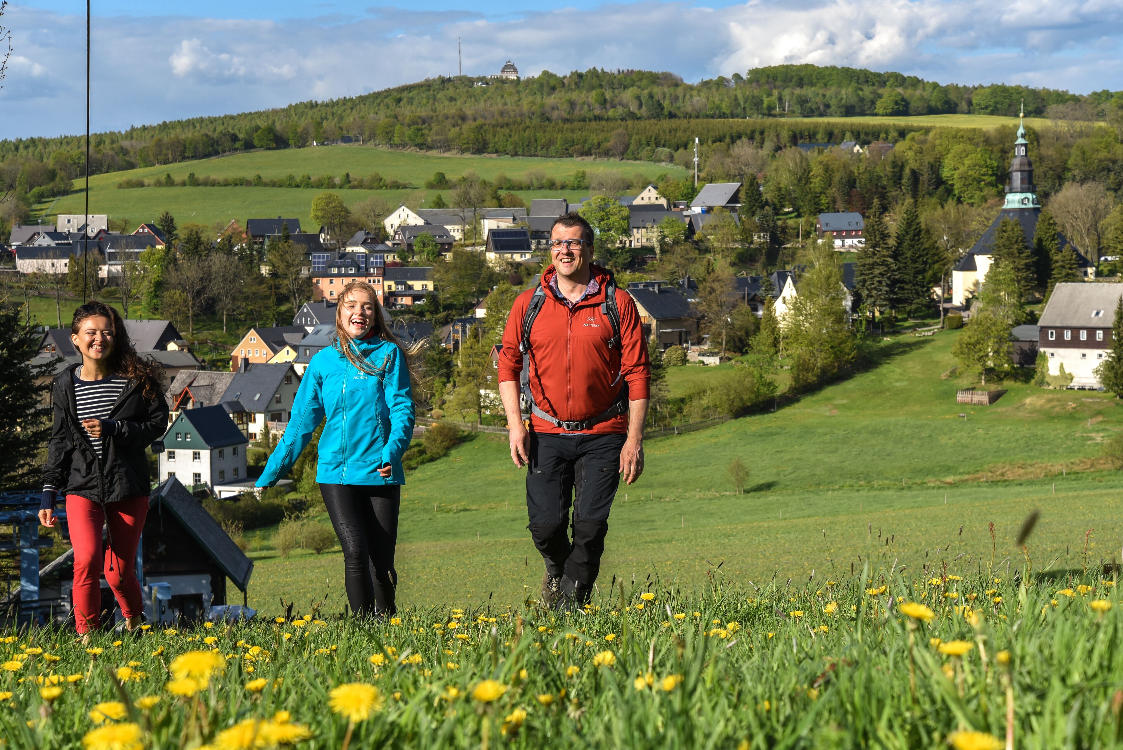 A group of people walking in a field with houses in the background.