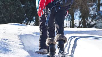 Deux personnes se promènent sur un sentier enneigé, avec des arbres en arrière-plan.