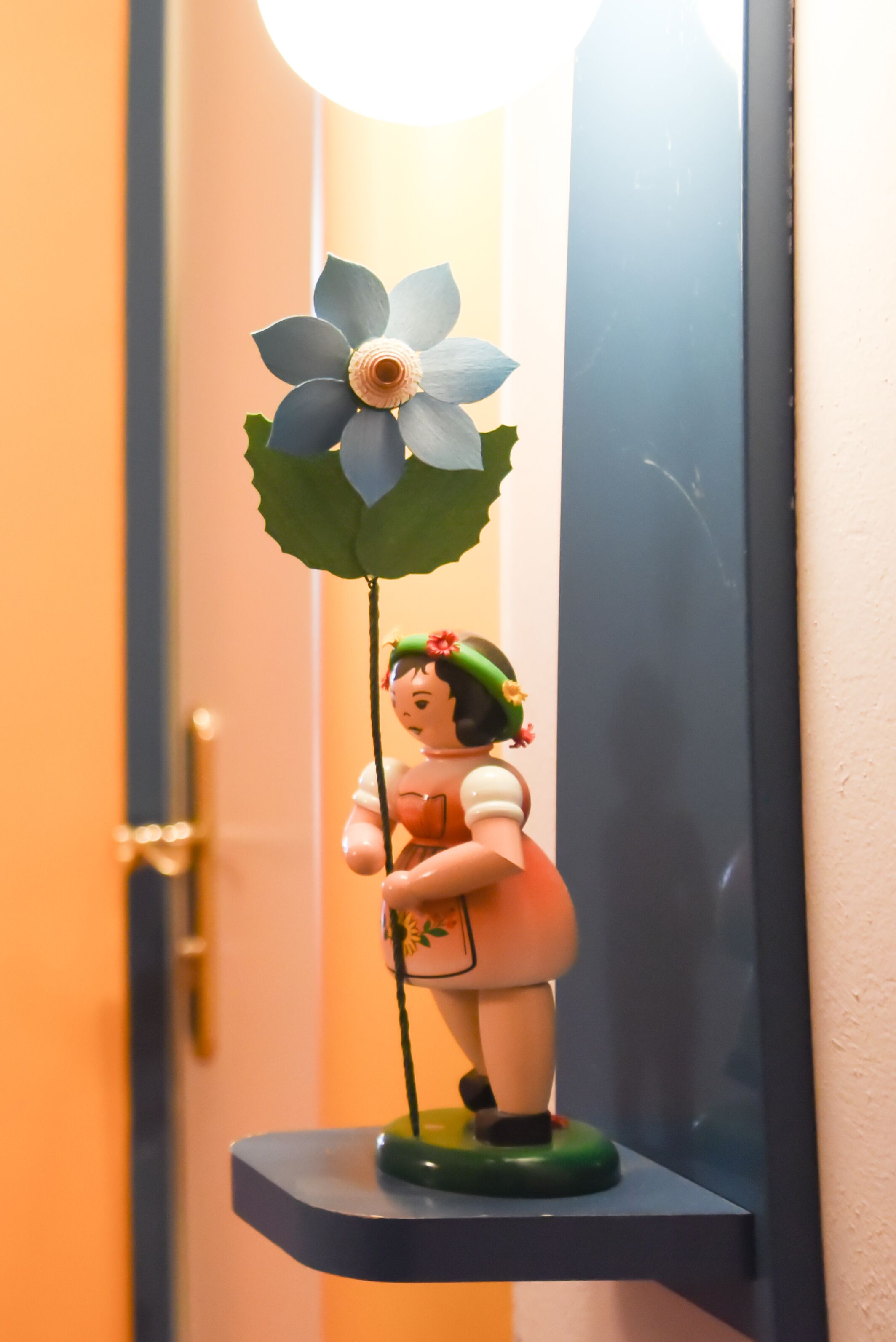 A figurine of a woman holding a flower on a shelf.