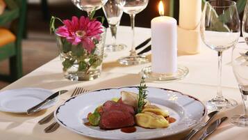 A dining table set with plates, cutlery, and a candle.