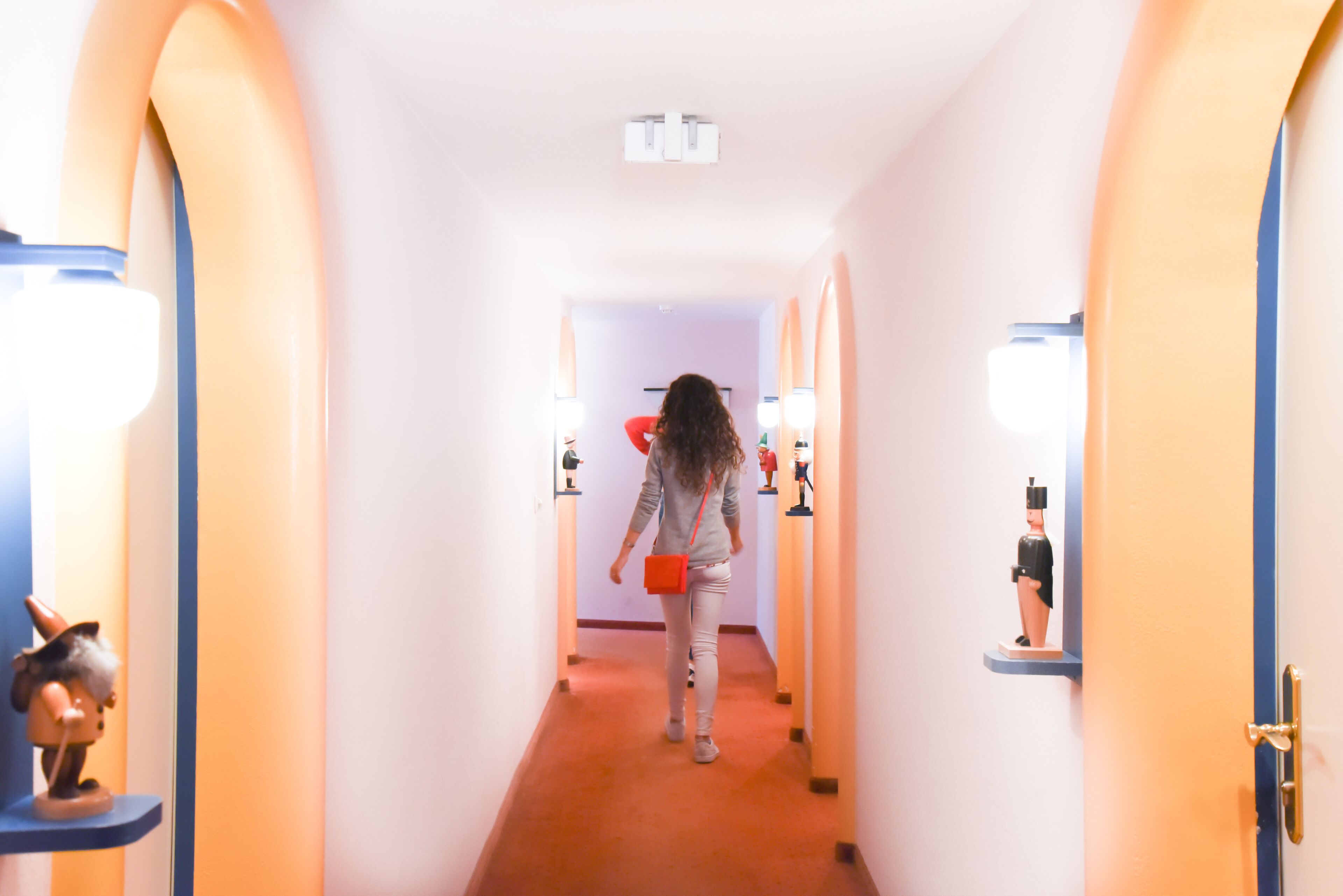 A hallway with a person walking towards a door.