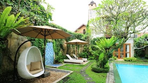 A poolside area with a hot tub, lounge chairs, and umbrellas. - Villa Puriartha (Ubud)