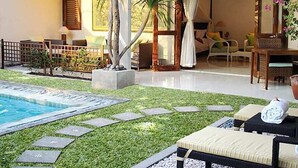 A poolside area with a lounge chair, a small table, and a potted plant. - Villa Puriartha (Ubud)