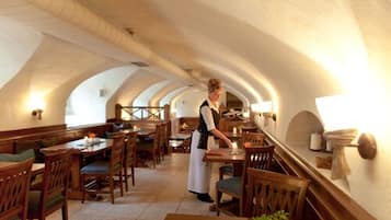 A restaurant with wooden furniture, a waitress, and a vaulted ceiling.