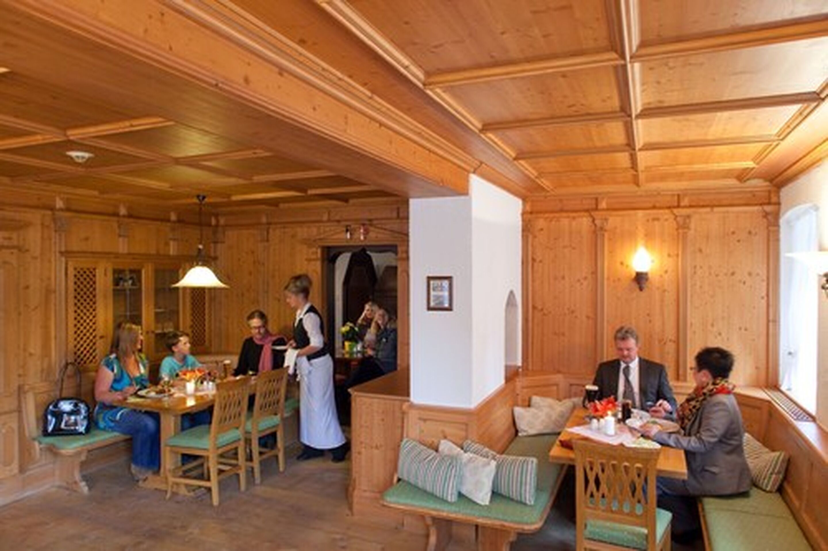 A wooden interior with a dining area, seating, and a visible door.
