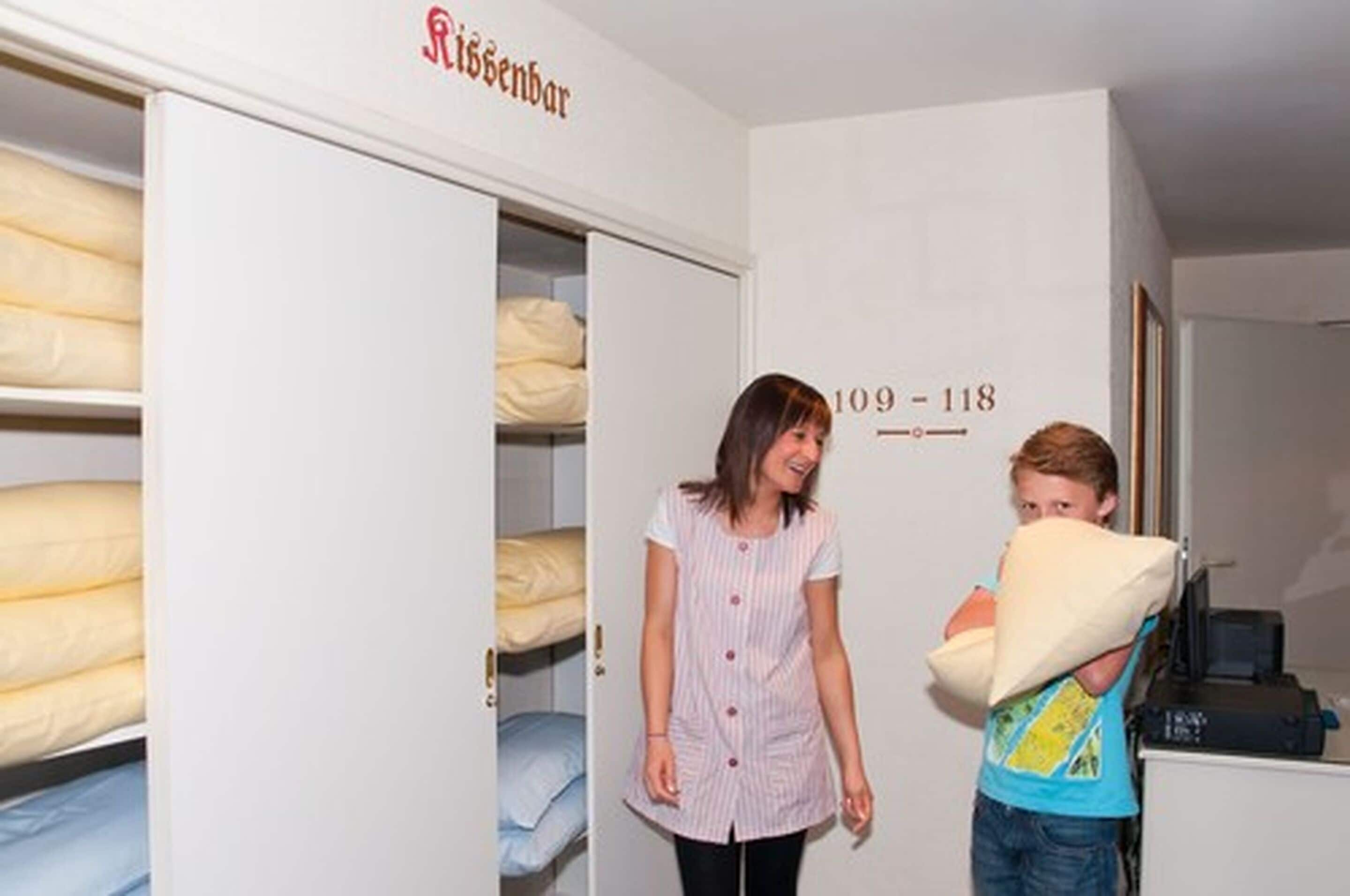 A room with bunk beds, a wardrobe, and a door with room numbers.