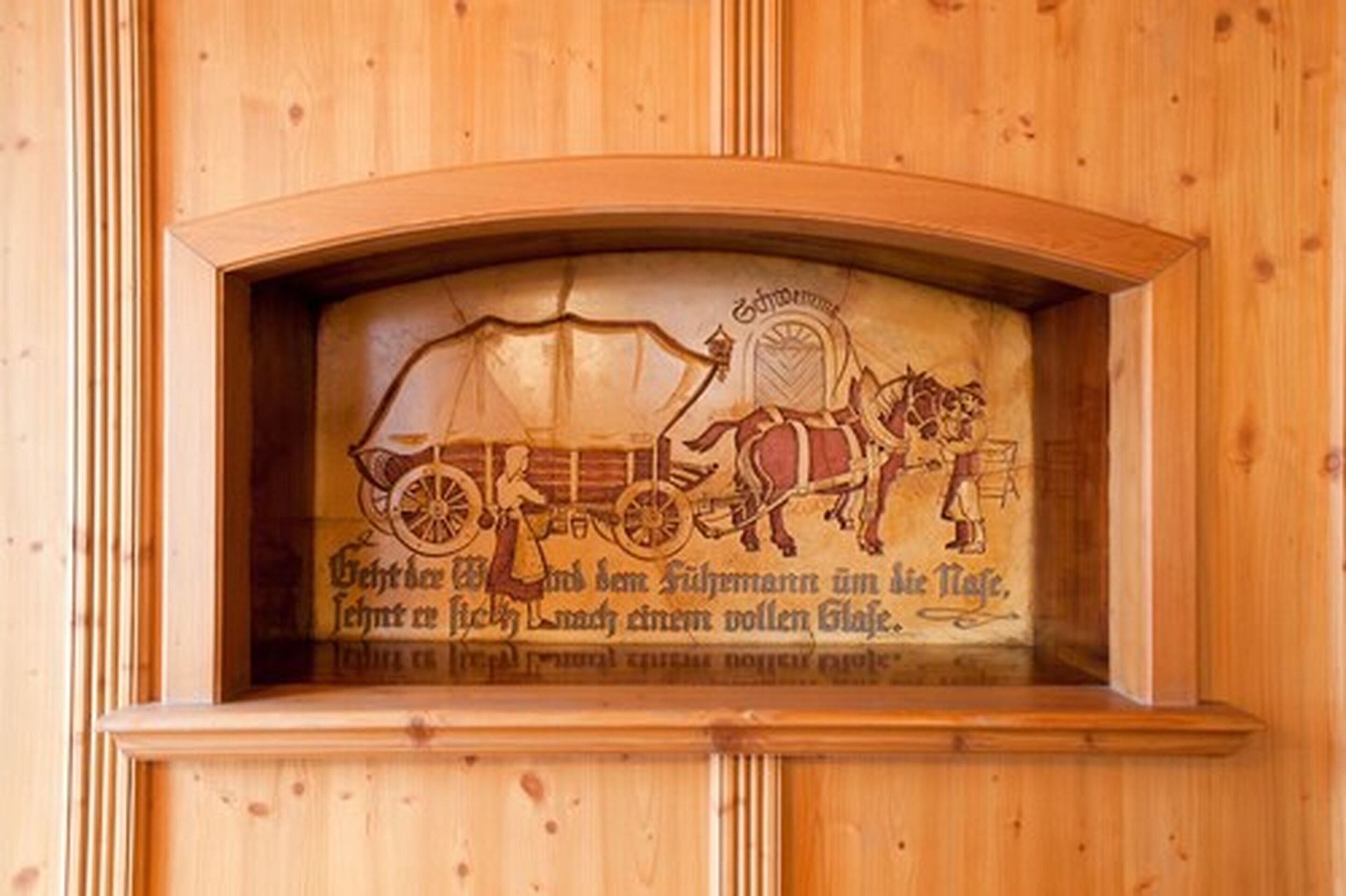 Pared de madera con un emblema tallado que muestra un carruaje tirado por caballos y texto.