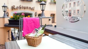 Una cesta de mimbre con revistas sobre una mesa frente a un edificio con un letrero que dice "Rostunde".