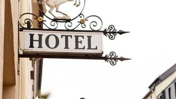 Segnaletica di un albergo con l'emblema di un cavallo e la scritta 'HOTEL' in un carattere tipografico classico.