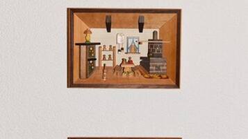 Three framed interior scenes with wooden frames, each depicting a different room layout with furniture and objects.