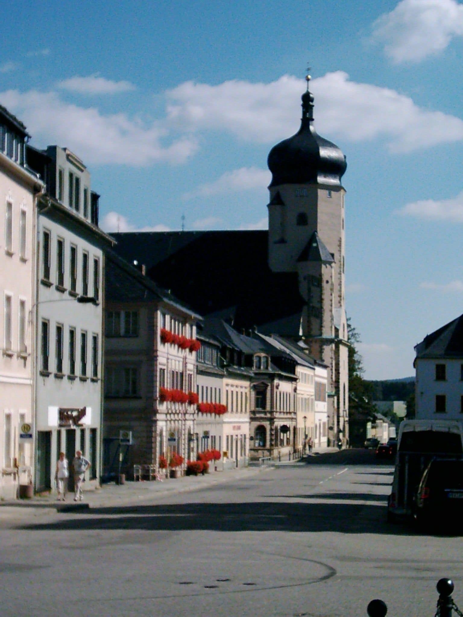 A street with historic buildings, a prominent tower, and a clear sky.