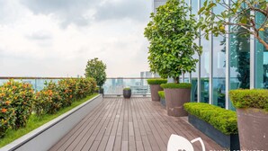 Terraza en la azotea con suelo de madera, plantas en macetas y vistas a la ciudad.